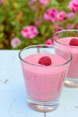 Raspberry smoothies with pink flowers on the background