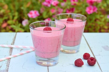 Raspberry smoothies with pink flowers on the background