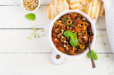 Traditional Italian Caponata and toast on a wooden white table. Sicilian caponata. Top view, above,...