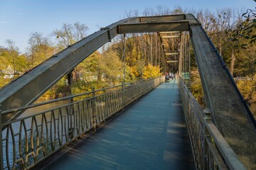 People walk along footbridge across Psekups mountain river. Resorts of Krasnodar Territory. Treatment and rest in foothills of North Caucasus. Goryachy Klyuch, Russia - November 5, 2020
