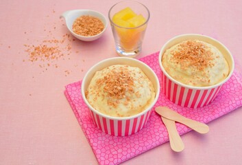 Pineapple coconut ice cream in cups topped with toasted coconut flakes
