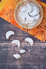 Putri Salju or crescent-shaped cookies coated with powdered sugar. Traditional Indonesian cookies to celebrate Eid al Fitr. Flat lay, wooden background