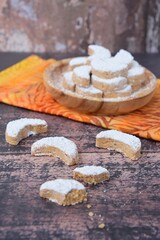 Putri Salju or crescent-shaped cookies coated with powdered sugar. Traditional Indonesian cookies to celebrate Eid al Fitr. wooden background