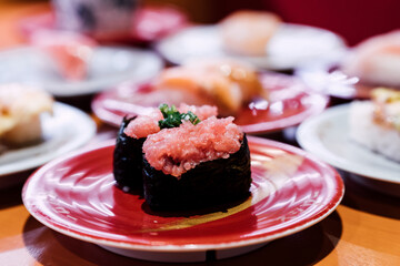 Sushi and Sashimi. Dishes of Sushi and Sashimi rolling on conveyer belt.