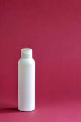 White plastic cosmetic lotion bottle mock-up on purple background. Hygiene, Beauty and body skin care concept. Copy space. Vertical photo. Selective focus.