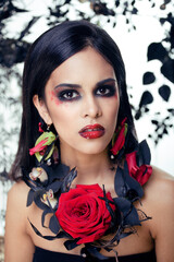 Fototapeta na wymiar pretty brunette woman with rose jewelry, black and red, bright make up a vampire closeup red lips