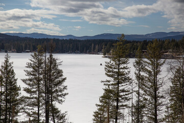 Frozen northern lake amongst pines and mountains