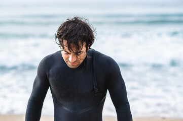 Medium shot young wet man with diving suit getting out of the sea