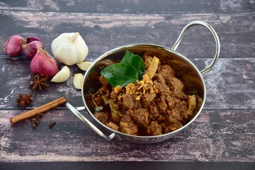 Beef Rendang, spicy beef stew from Indonesia. Served in a wok on wooden background