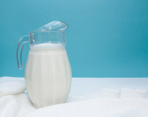 A jug of fresh milk on a white and blue background. Farm dairy product concept. World Milk Day. copy space for text