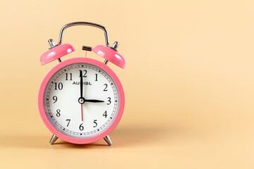 Pink alarm clock on a beige background. Time Concept. Place for your text.