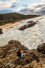 Woman looking over a dramatic beach scene. Plettenberg Bay, South Africa. September 2019