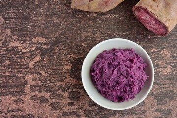 Obraz na płótnie Canvas Mashed purple sweet potato in a bowl on wooden background. flat lay, 
