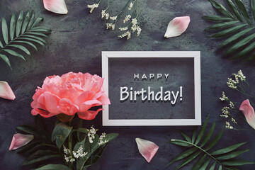 Happy birthday card with peony and palm leaves. Flowers, petals and exotic leaves around white...