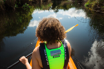 Mixed race woman rowing a canoe down a stream near Plettenberg Bay, South Africa.