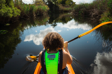Mixed race woman rowing a canoe down a stream near Plettenberg Bay, South Africa.