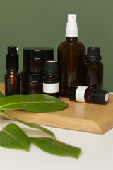 Various brown glass cosmetics bottles on green background
