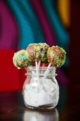 Variety of colorful Chocolate cake pops in a transparent jar. Close-up, selective focus