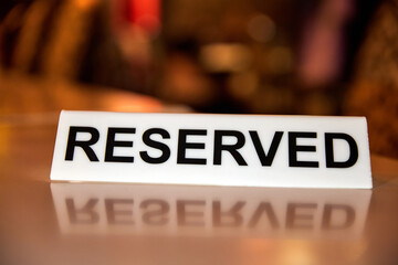 Plastic plaque with the inscription Reserved on the restaurant table.
