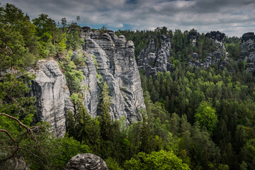 Fototapeta na wymiar View from viewpoint of Bastei Bridge in Saxon Switzerland Germany to the town at the mountain on a cloudy day