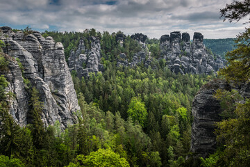 Fototapeta na wymiar View from viewpoint of Bastei Bridge in Saxon Switzerland Germany to the town at the mountain on a cloudy day