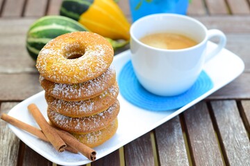 Stack of pumpkin donuts with a cup of coffee