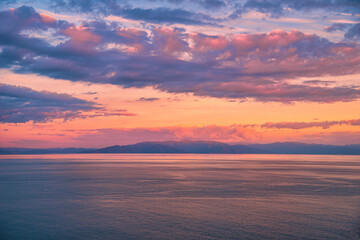 Naklejka na ściany i meble Beautiful cloudscape and dramatic sunset over mountain and sea.
