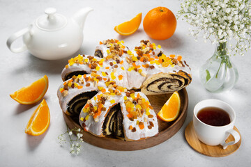 Poppy sweet roll with oranges on white table.