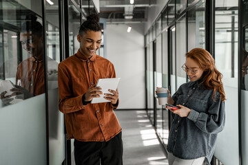 happy african american student using digital tablet near classmate with smartphone