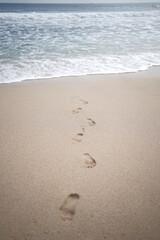 footprints on the white sand of the beach