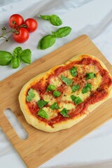 pizza with tomato sauce, mozzarella and basil leaves on wooden board