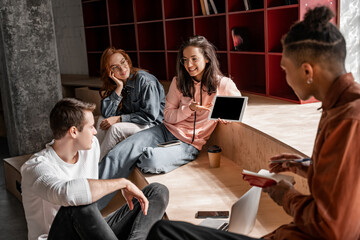 happy student pointing at digital tablet with blank screen near interracial classmates