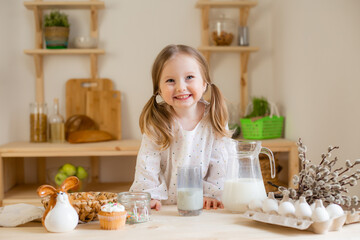 A cute little girl drinks milk at home in a wooden kitchen. Milk Day