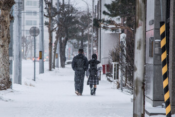 japanese students in uniforms walking in the snow