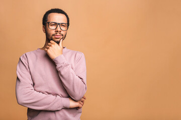 Thinking black Afro American man with serious expression looking, posing isolated against beige background.