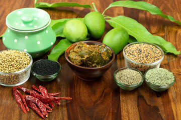 Aam ka achar or Mango Pickel or Homemade Mango Pickle or Kairi Loncha in a wodded bowl with Spices and jar and Raw Mango, selective focus