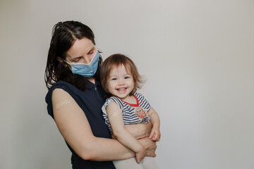 mother and daughter, a child after vaccination. A woman in a medical mask. Happy joyful child