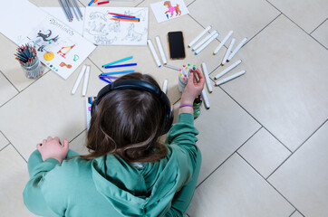 Overhead shot of a teenage girl drawing with headphones and a mobile phone. Copy space background.
