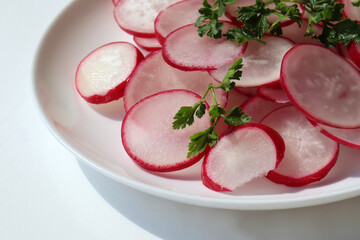 Obraz na płótnie Canvas Fresh radish salad with parsley on white background. Top view, copy space. Spring summer vegetable salad on white plate