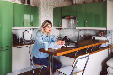 business woman looking at mobile phone while at home in the kitchen