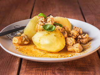 Young boiled potatoes with chicken goulash on a light plate