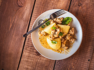 Boiled potatoes and fried chicken fillet on a round plate