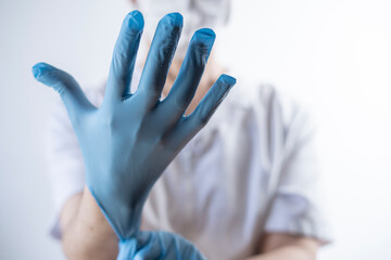 nurse in white gown putting on gloves