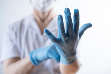 nurse in white gown putting on gloves