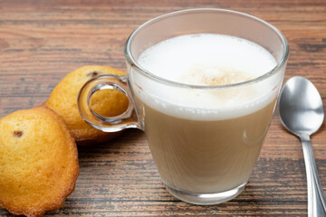 tasse de café au lait et madeleine sur une table