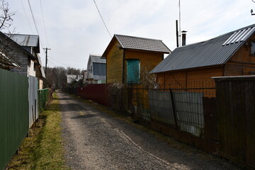Fototapeta na wymiar Street in the horticultural Association. Country houses behind high fences. Early spring.