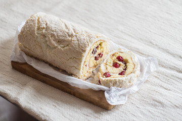 Meringue roll cake with cream and fresh cranberries. Roulade, summer dessert. Horisontal orientation, selective focus.
