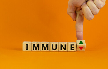 Corona immune and medical symbol. Doctor turns a cube and changes the expression 'immune down' to 'immune up'. Beautiful orange background. Medical, immune level concept. Copy space.