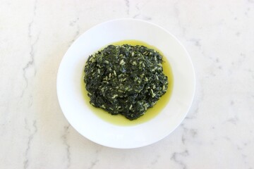 On a white marble table, a Spanakorizo Greek dish of spinach and rice is isolated.