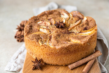 Apple pie with cinnamon on wooden board, light concrete background. Semolina cake with apple and spices. Homemade mannik.